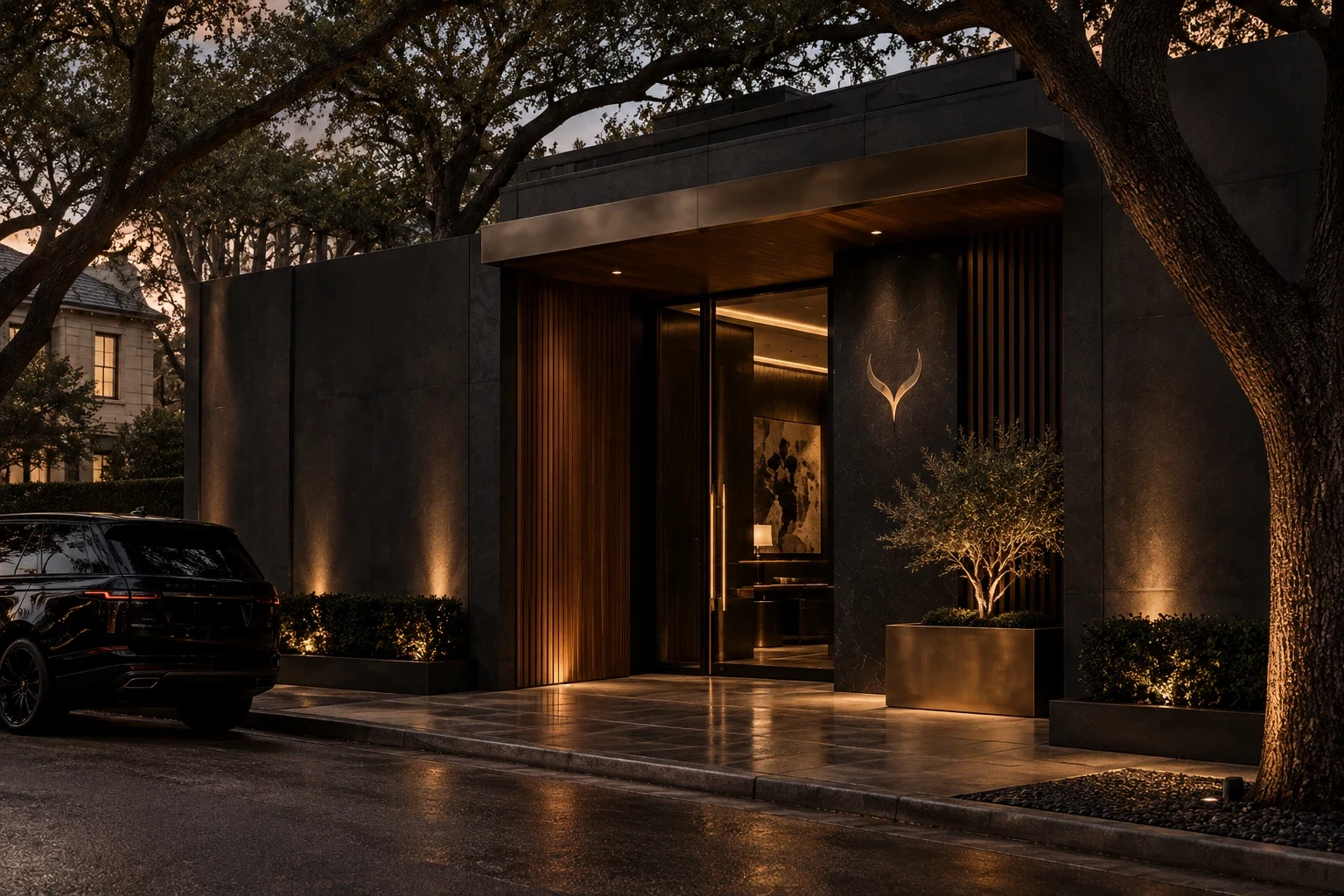 The Houston flagship entrance at dusk: a dark stone facade under live oaks, a brass canopy, a glowing horn mark beside a tall glass door.