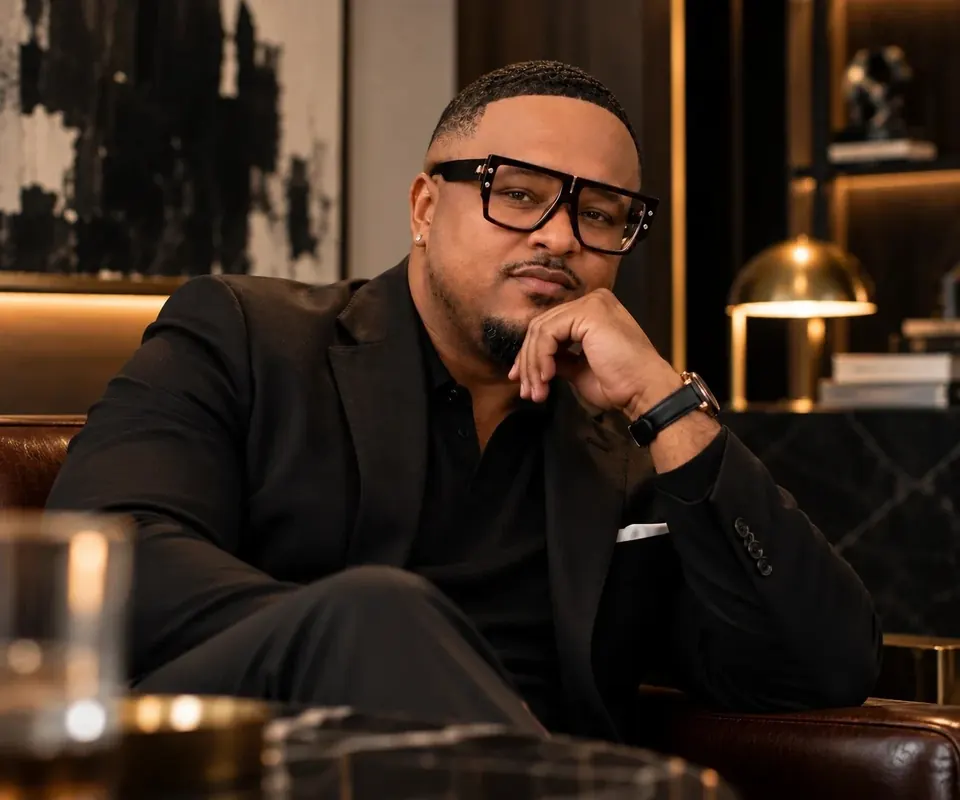Brennon Jackson, founder of EYEGASMIC, resting his chin on his hand in a dark library.